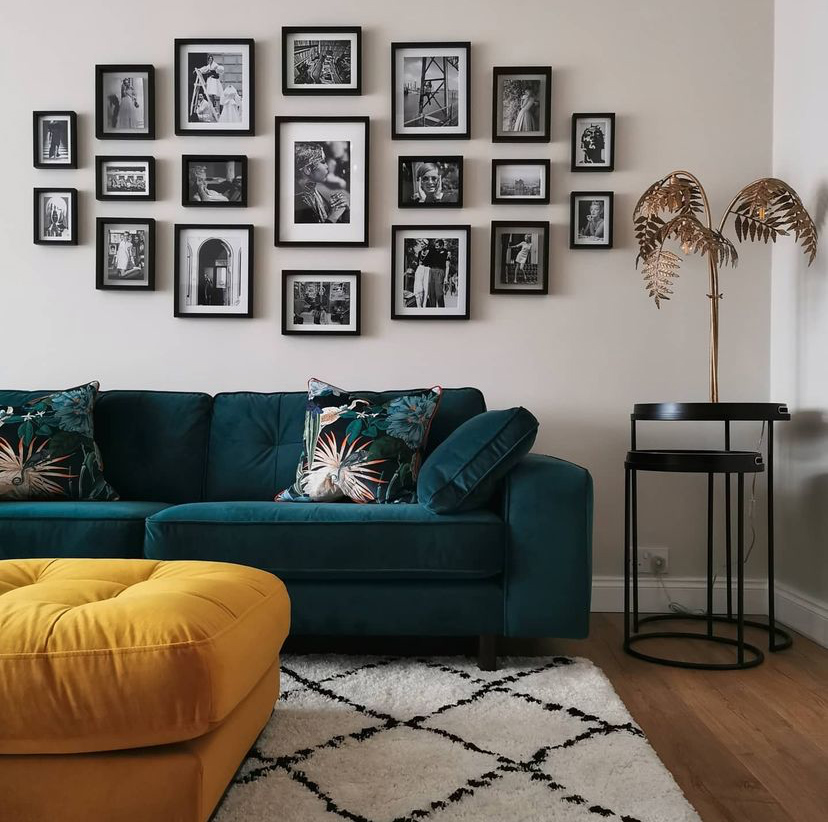 Dark teal velvet sofa styled simply with matching cushions and a gorgeous black and white gallery wall