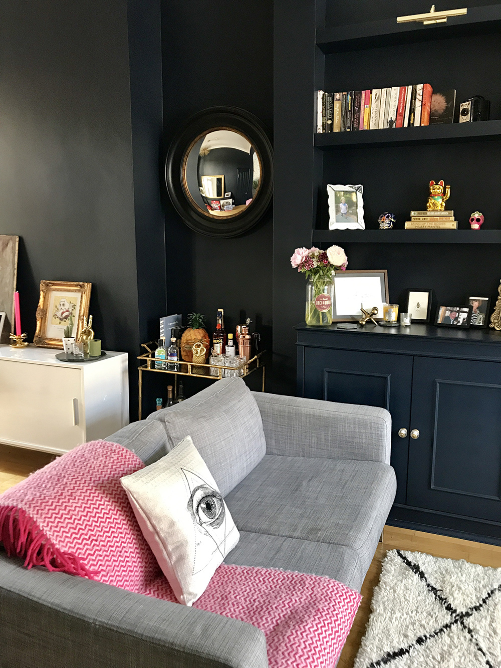 After: Living room makeover. Quirky and stylish home accessories give this dark and moody living room the wow factor. The walls are painted in Basalt by Little Greene, which works great with gold accents.