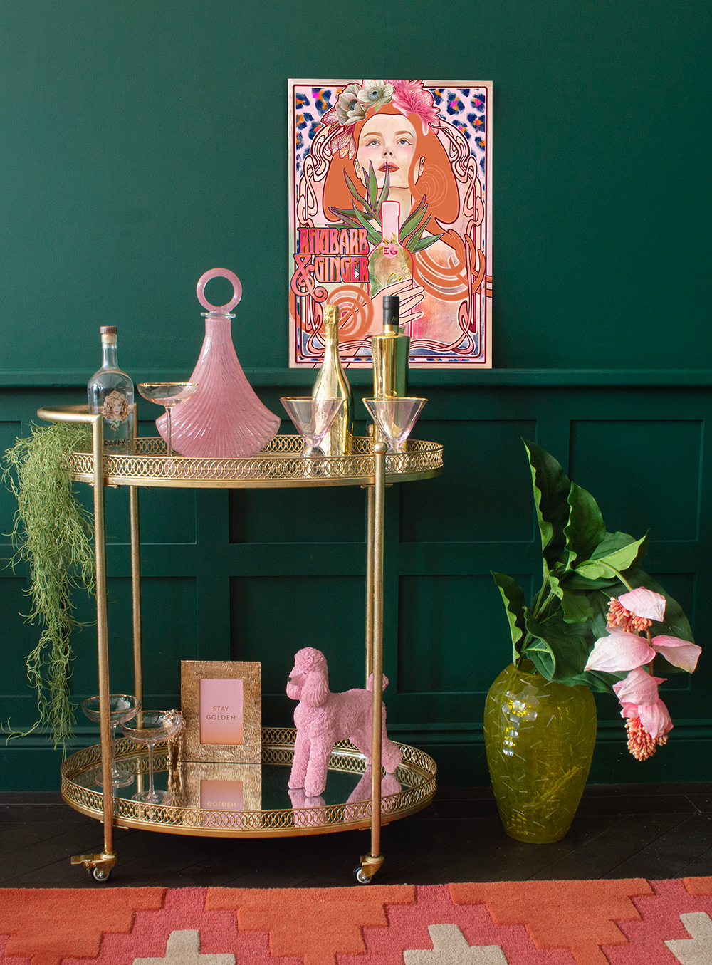 Create your own home bar with his gorgeous antique gold bar cart. Styled with pink glassware, faux plants and a colourful art print