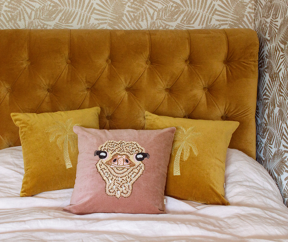 Mustard velvet bed with pink and mustard velvet scatter cushions by Audenza.