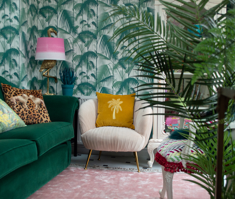 Pink and green tropical living room inspiration with green patterned wallpaper and blush pink velvet armchair.