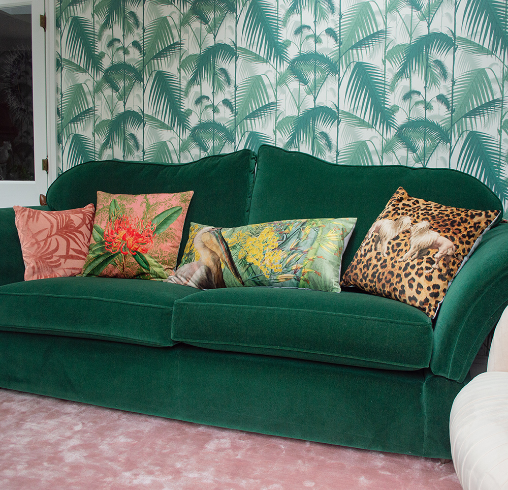 Colourful, patterned scatter cushions and green velvet sofa