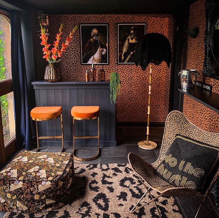 Maximalist home bar with leopard print wallpaper and leopard print home accessories.