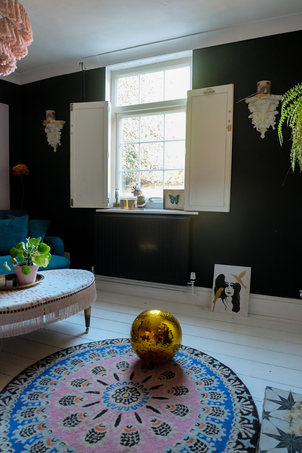 Black and moody decor with white painted floorboards and colourful accents