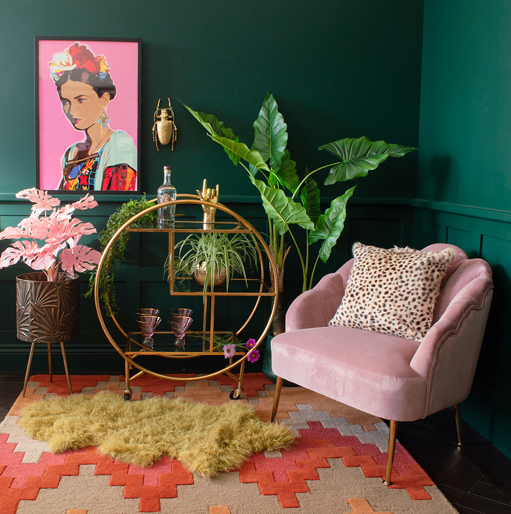 Moody, green living room decor with colourful and bold Frida Kahlo style self portrait and gold luxe round drinks trolley
