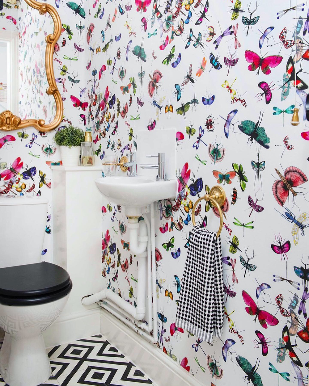 Small toilet decor inspiration with Christian Lacqoix moth wallpaper and monochrome lino flooring
