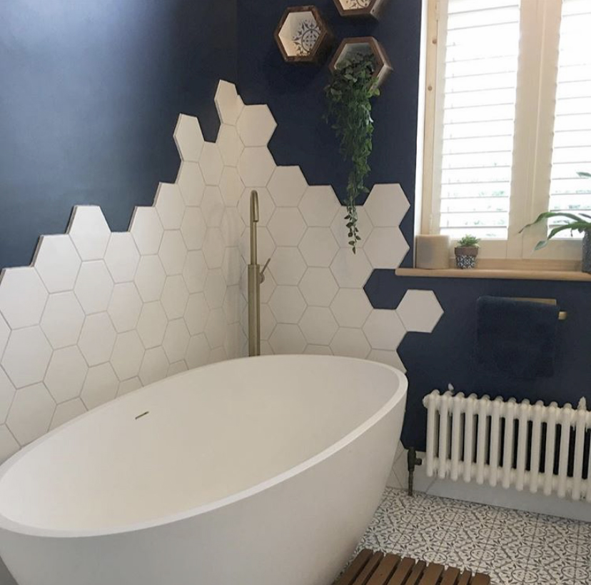 Navy blue and white bathroom decor with white hexagon wall tiles and white Windsor radiator
