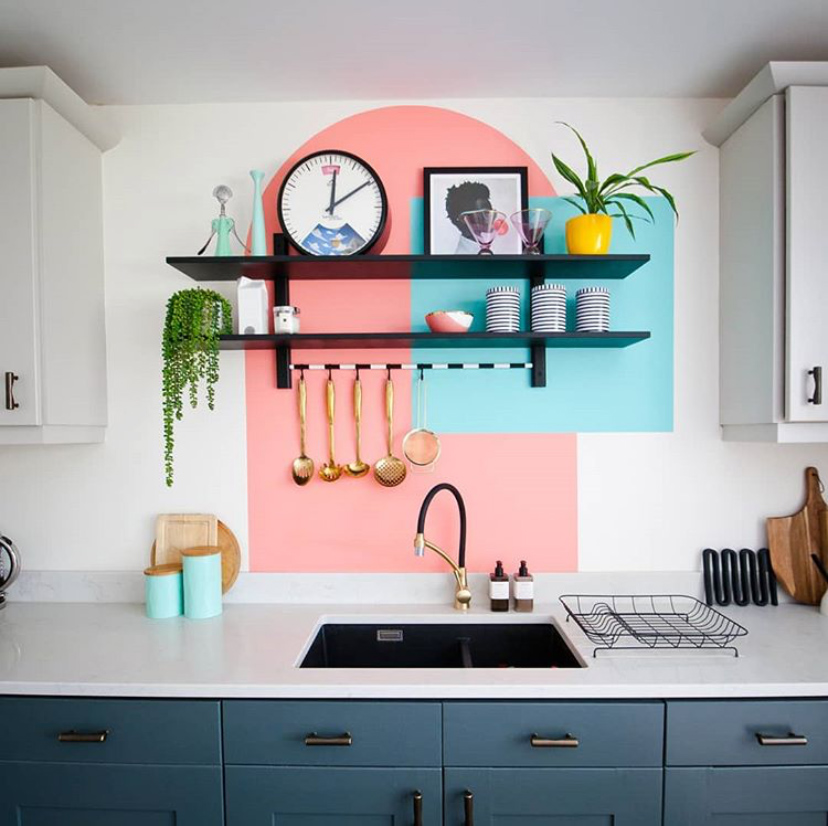 Quirky kitchen decor with colourful painted shapes behind black shelving 