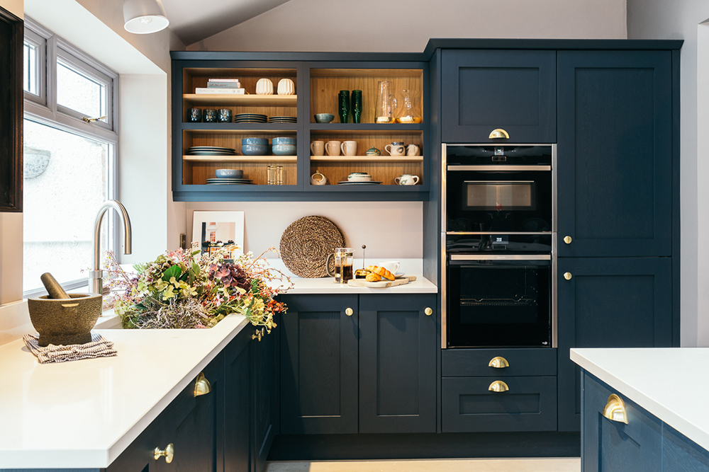 Contemporary kitchen design with navy blue cupboards and brass handles