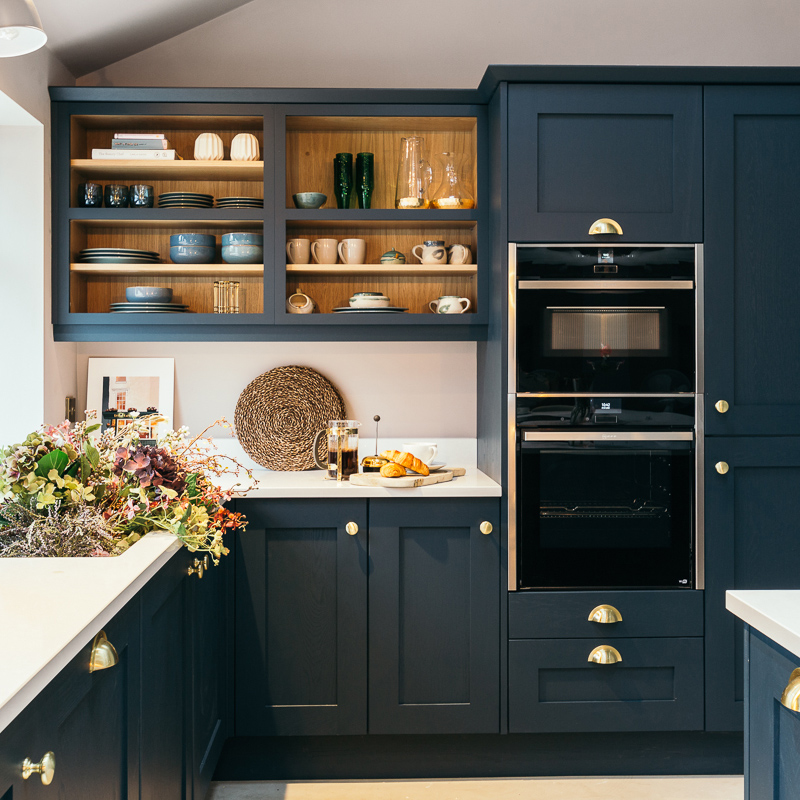 Contemporary kitchen design with navy blue cupboards and brass handles