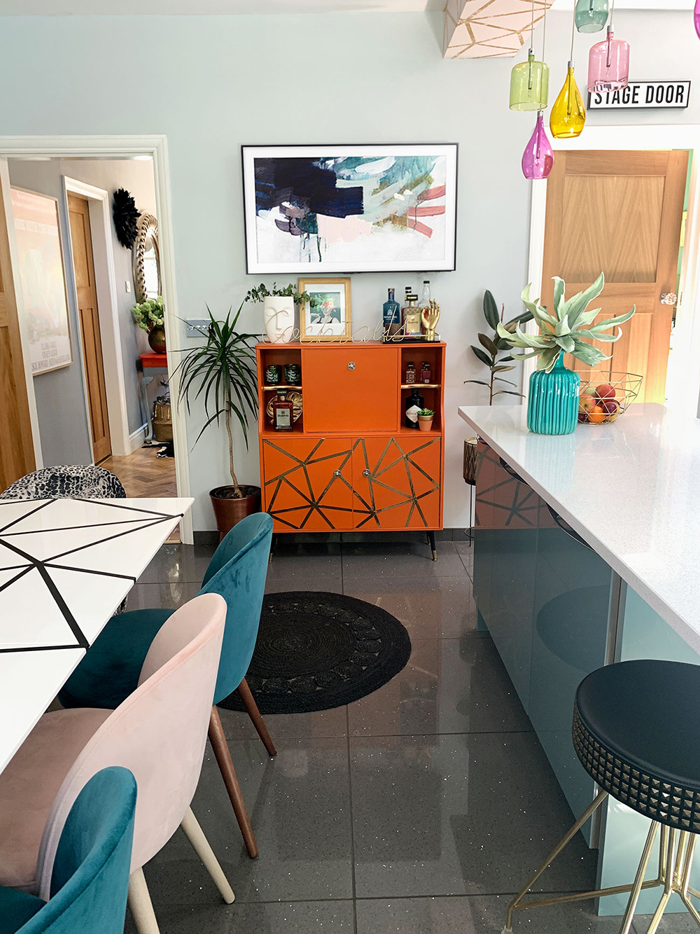 Pink and blue modern kitchen with colourful glass lights and geometric wallpaper