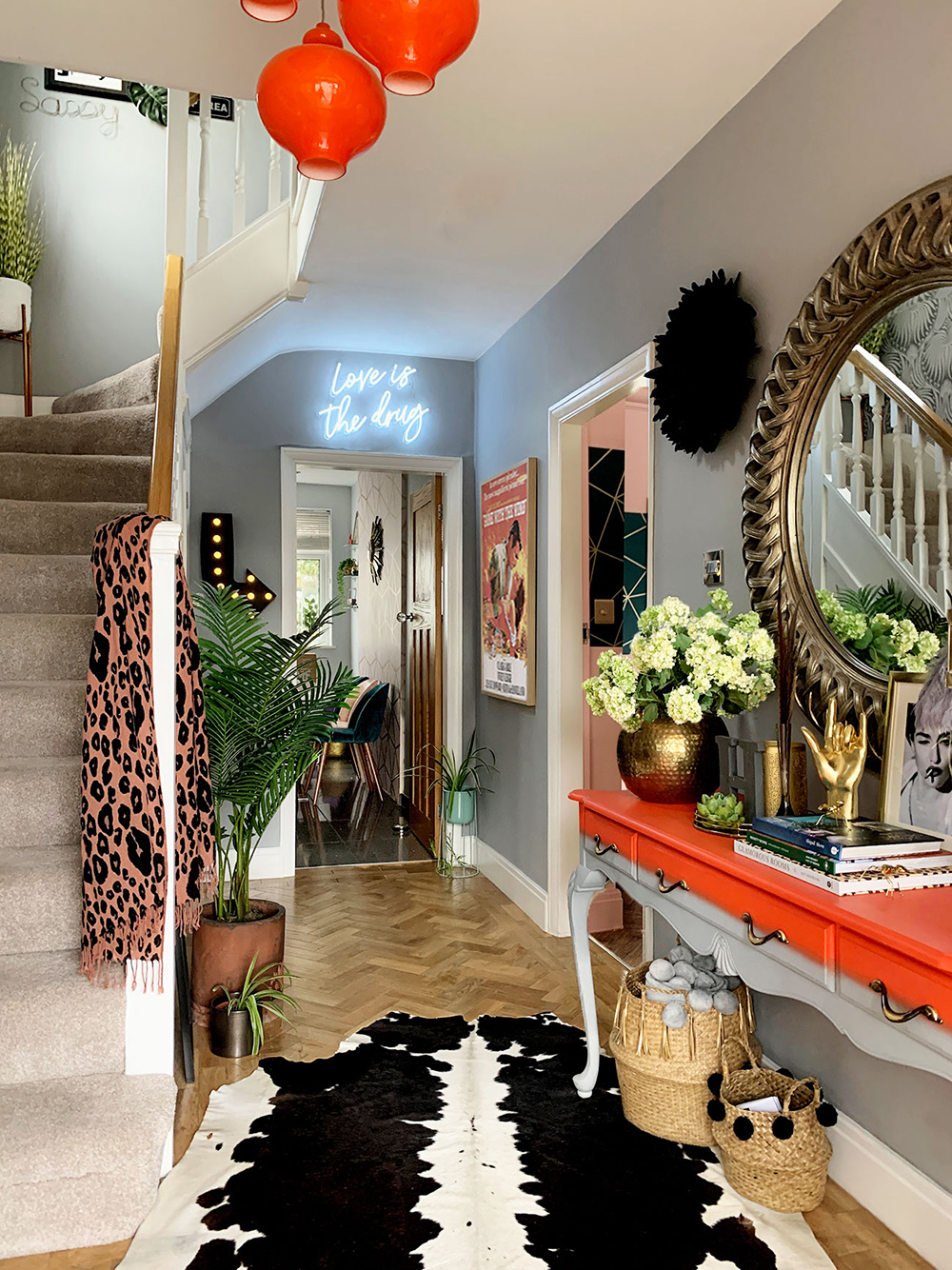 Eclectic hallway inspiration - pale grey and bright orange colour palette with cowhide rug and herringbone floor