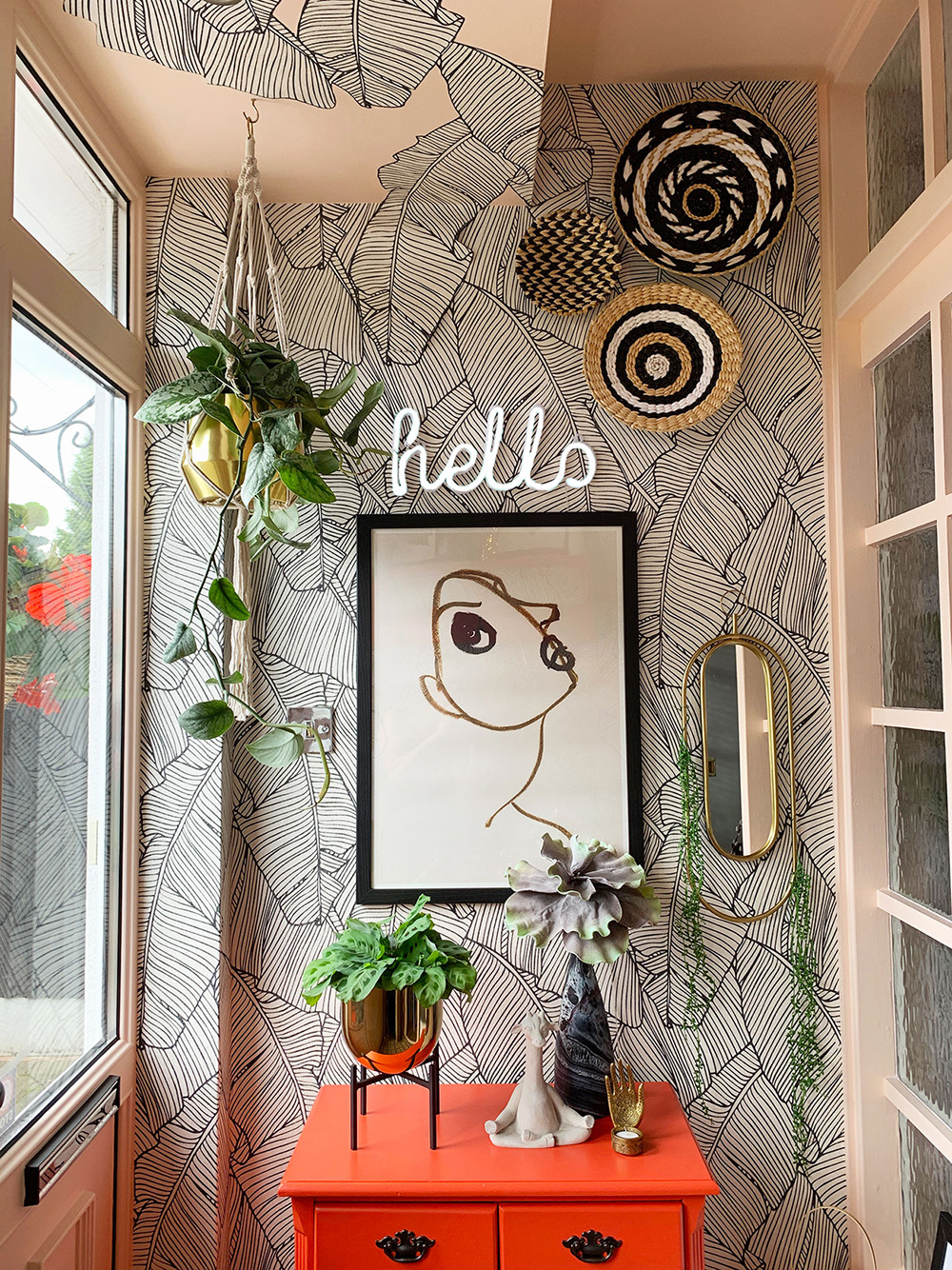 Quirky porch decor inspiration with orange cabinet and monochrome patterned wallpaper