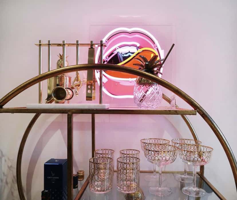 Pink neon lips styled beautifully on our gold round drinks trolley