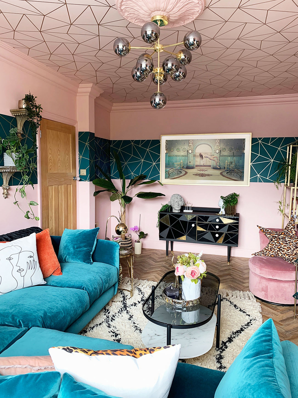 Pink and teal eclectic living room with geometric wallpaper and velvet furniture