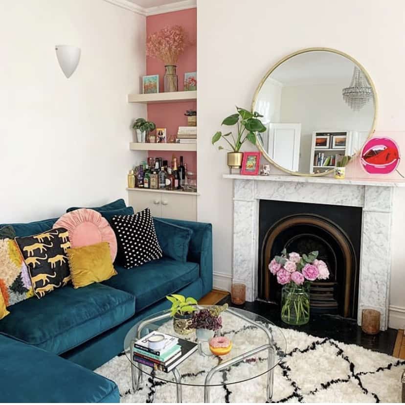 Pink and white living room inspiration with lush house plants, navy blue velvet sofa and berber style rug