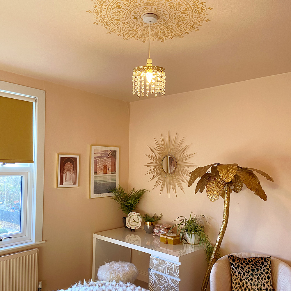 Gold ceiling medallion stencil in blush pink bedroom with gold accessories