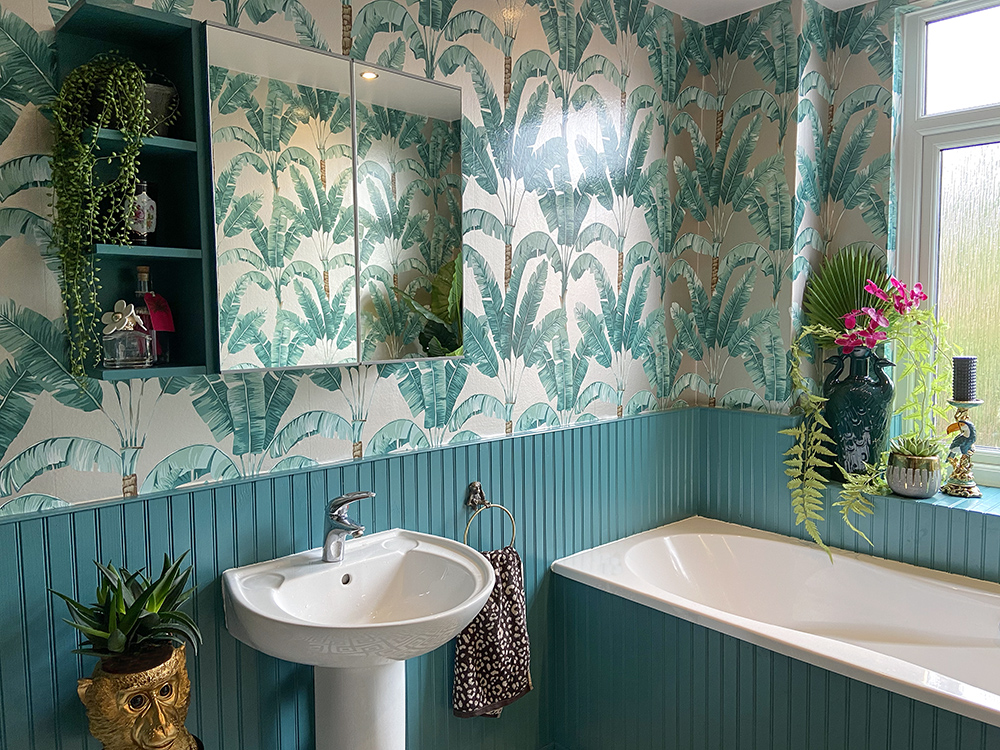 Tropical patterned wallpaper with artificial house plants and gold monkeys to give a jungle feel
