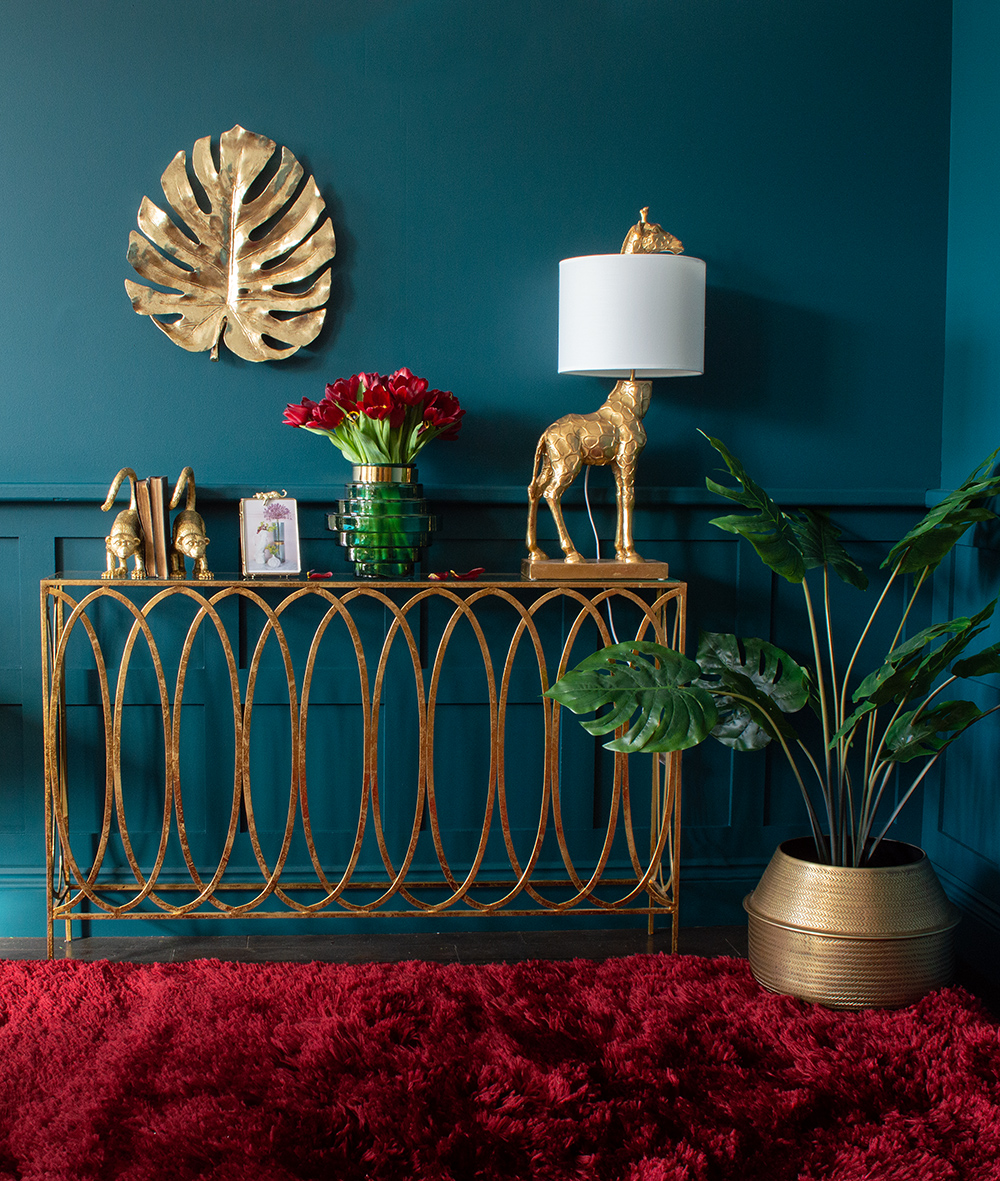 Moody blue living room with gold console table and quirky giraffe lamp 