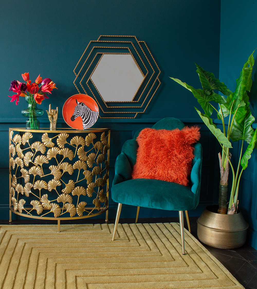 Gold ginkgo leaf console table with mustard wool rug and pops of bright orange home accessories