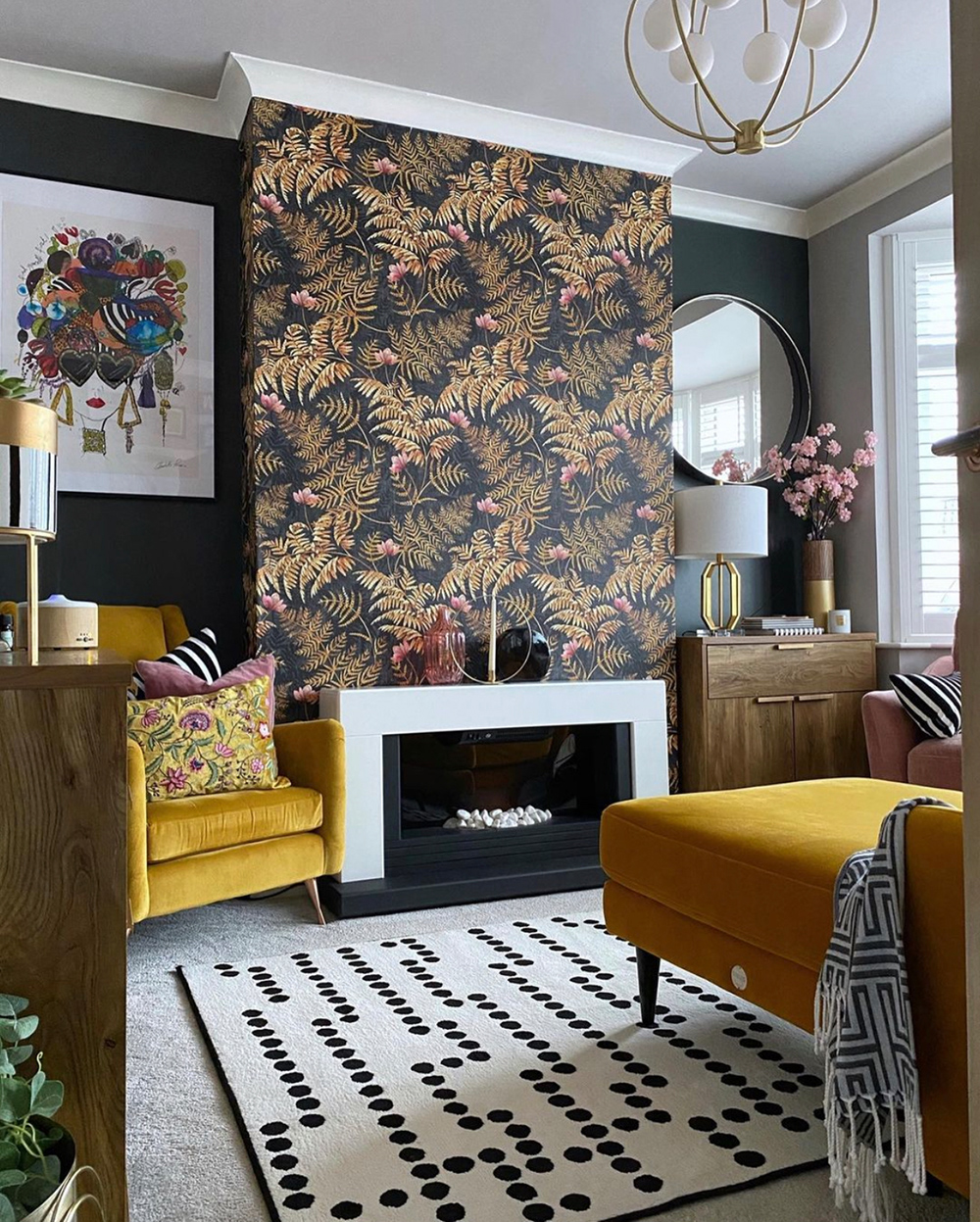 Eclectic living room decor with patterned wallpaper and yellow velvet sofa and armchair