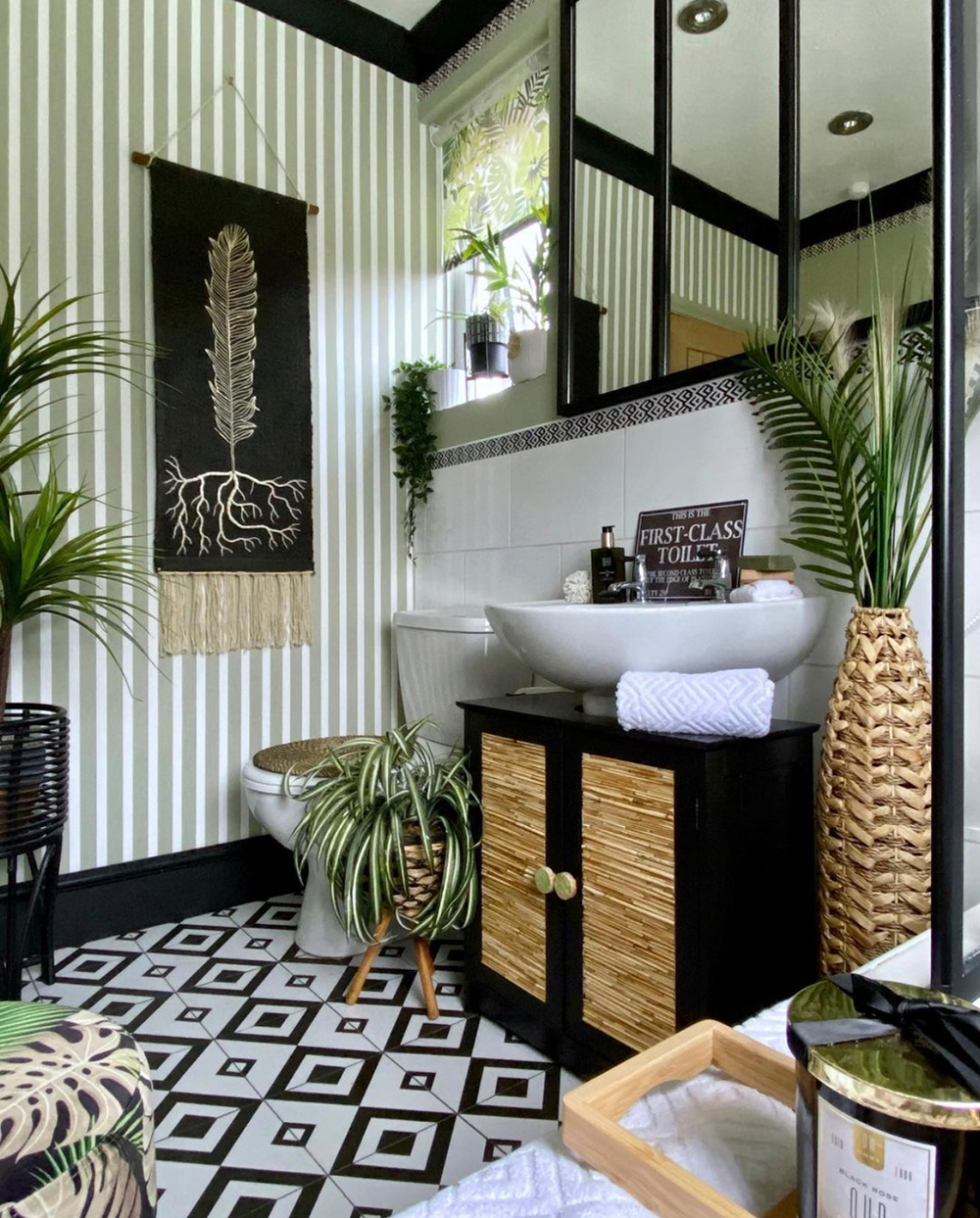 Green and black bathroom with monochrome patterned vinyl floor and lush house plants
