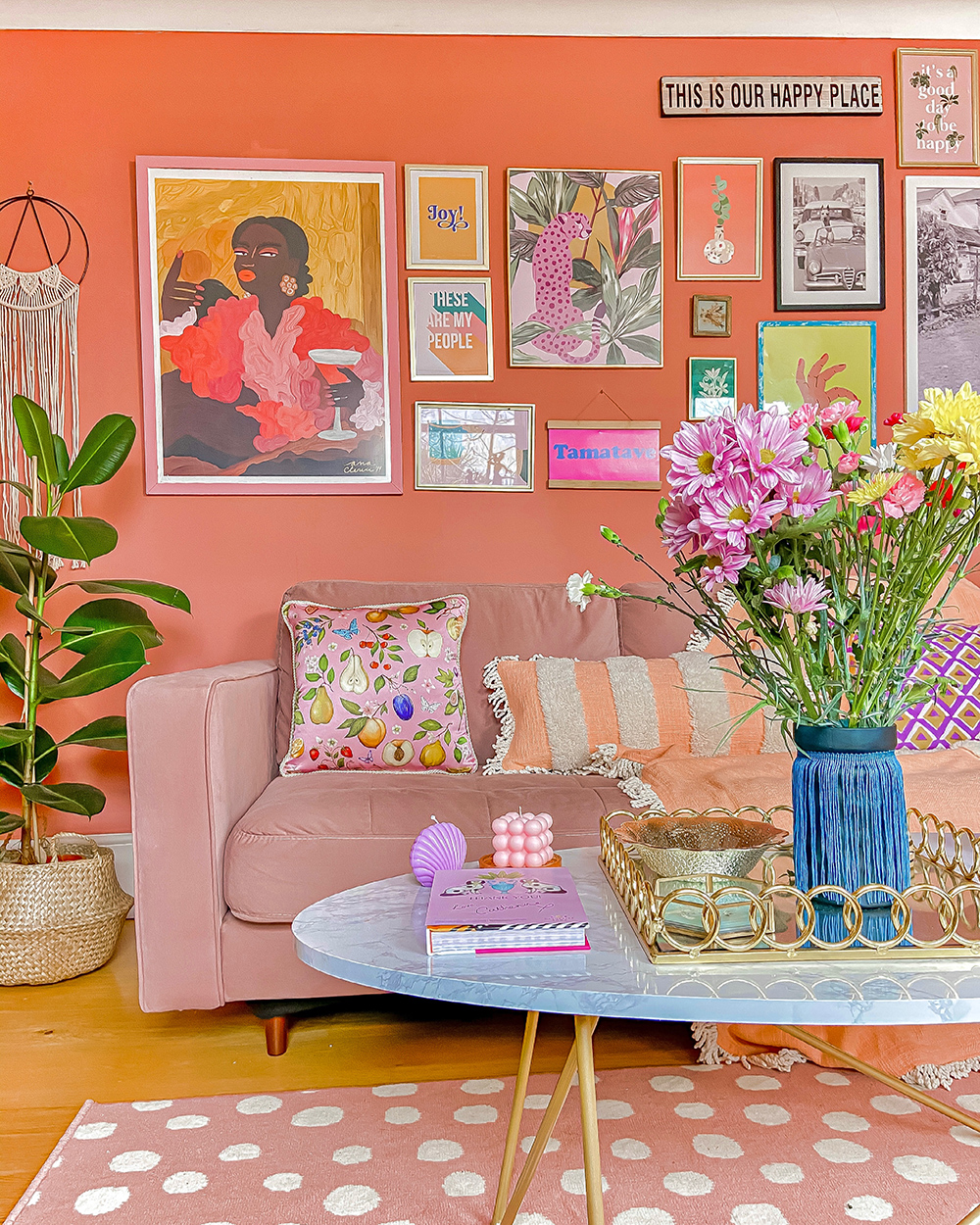 Peach and pink living room decor with a quirky gallery wall and pink velvet sofa