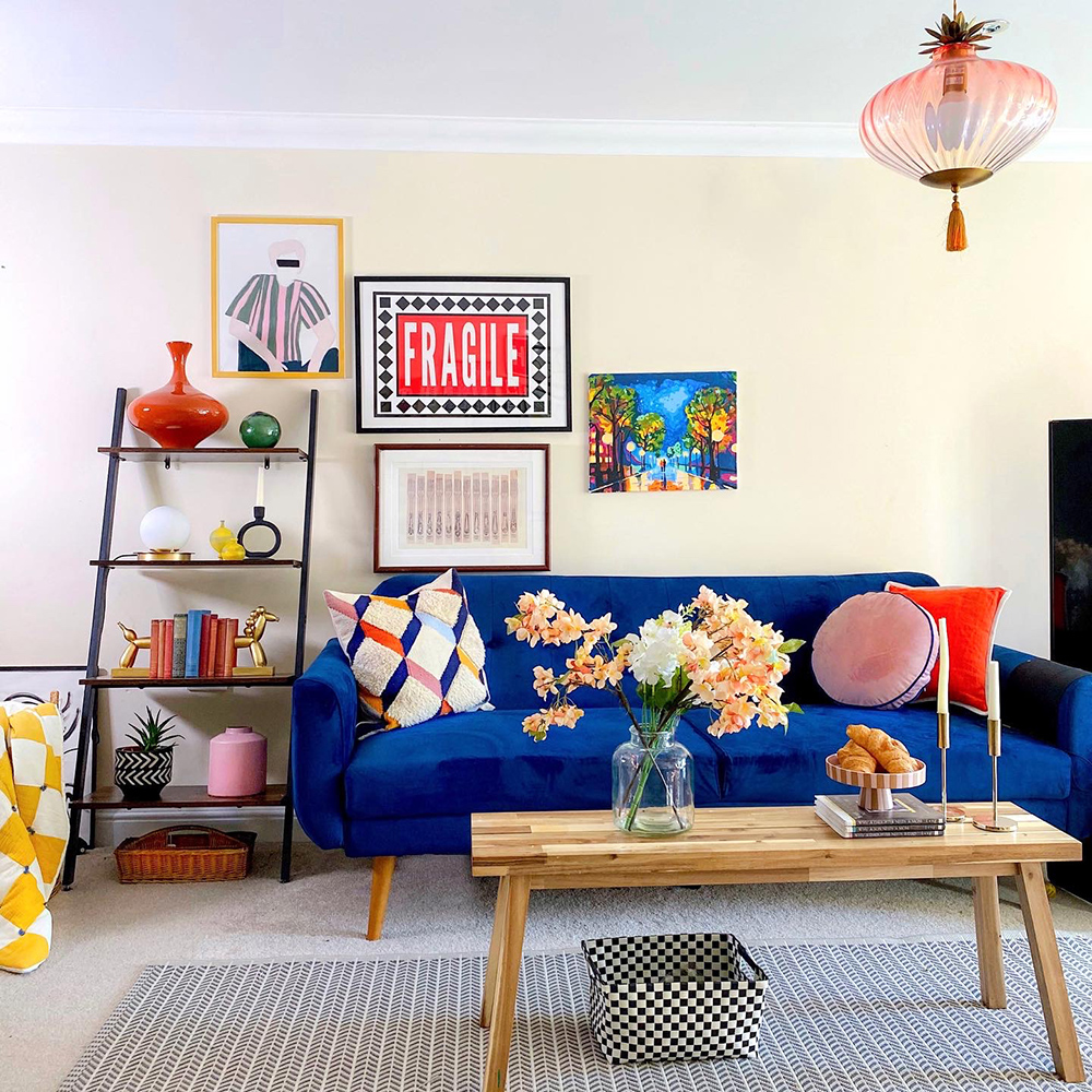 Eclectic living room decor - quirky art and electric blue velvet sofa give this living room a glamorous vibe