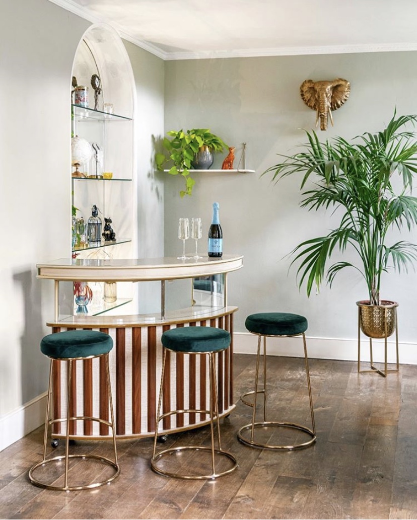Create your own sophisticated home bar with lush green house plant, elephant head wall decor and velvet bar stools