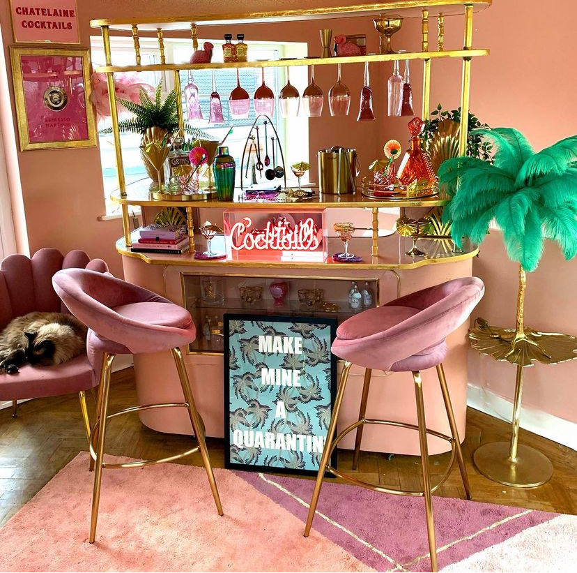 We are obsessed with this pink home bar by Interior Curve! Pink velvet stools, cool glassware, ostrich floor lamp - it's got it all!