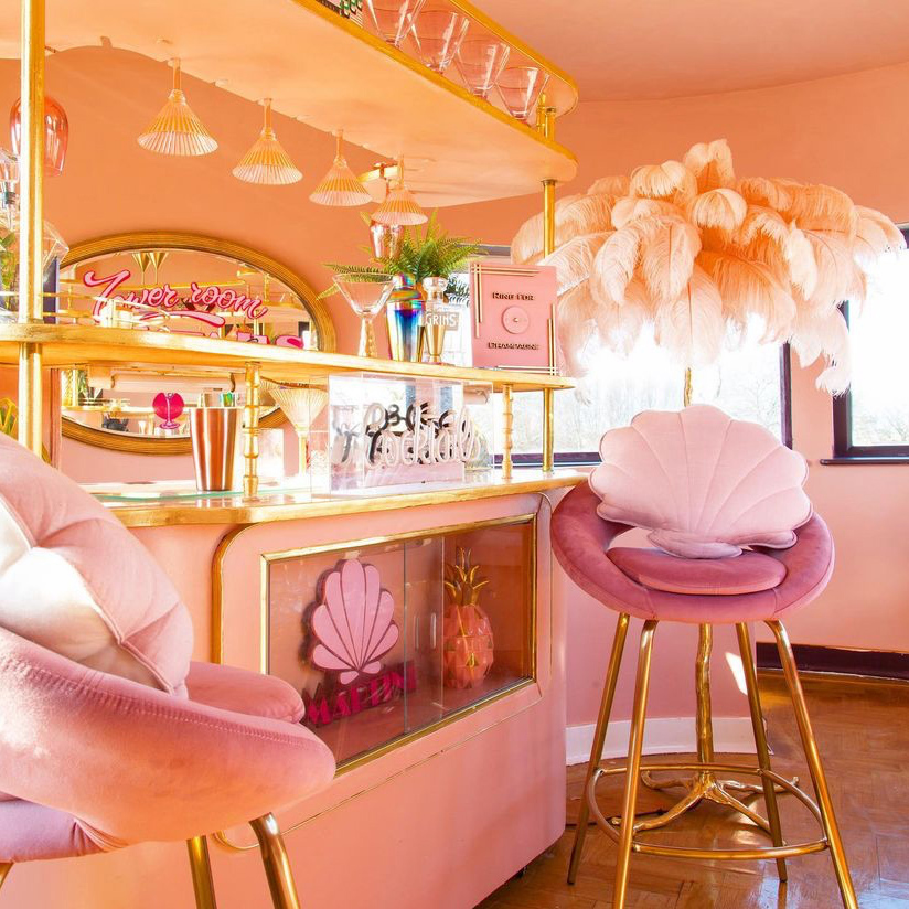 We are obsessed with this pink home bar by Interior Curve! Pink velvet stools, cool glassware, ostrich floor lamp - it's got it all!