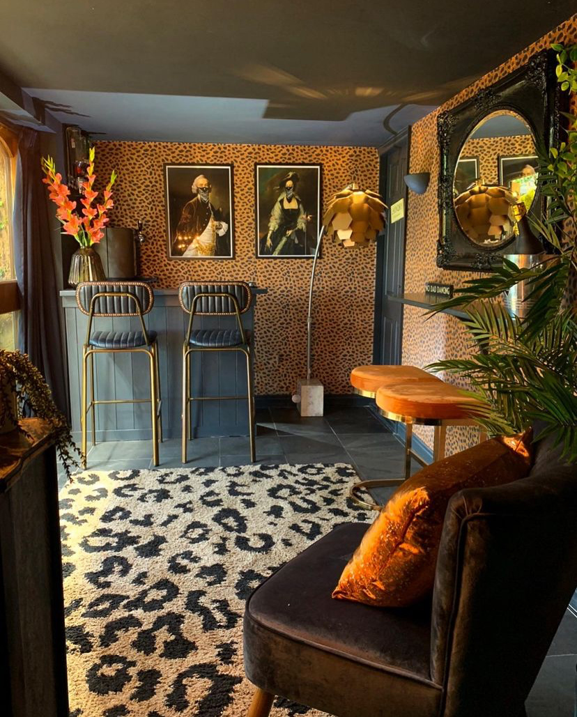 Dark and moody home bar by Sally Does Sassy. With leopard print wallpaper, armchairs and rug, what's not to love?!