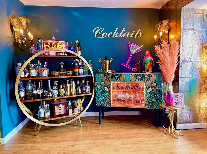 Home bar ideas - colourful and glamorous cocktail corner with gold round drinks trolley, vintage sideboard and cool glassware