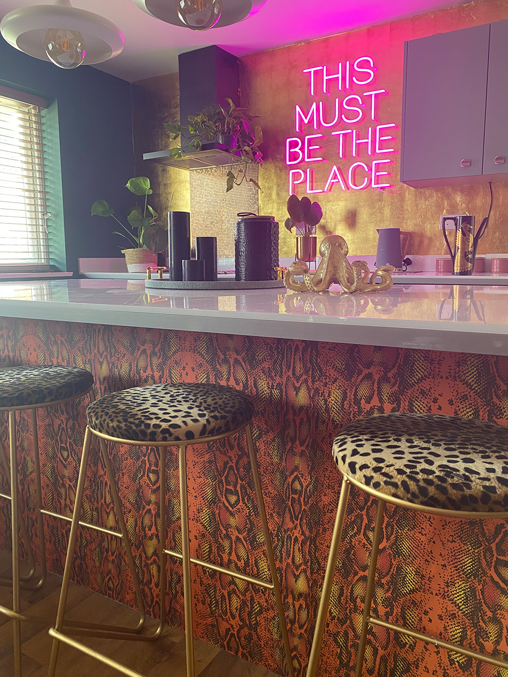 Eclectic kitchen design with This Must Be The Place pink peon sign. We love the clashing leopard print bar stools and snakeskin wallpaper. Image @inside.number.twelve