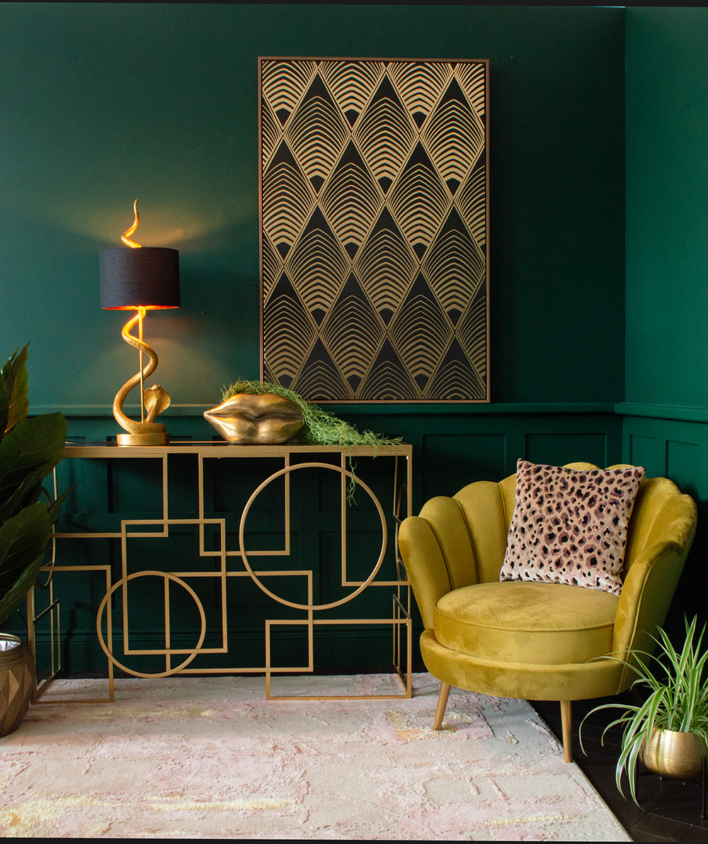 Dark green living room with mustard velvet armchar, art deco style artwork and gold console table. All available from Audenza