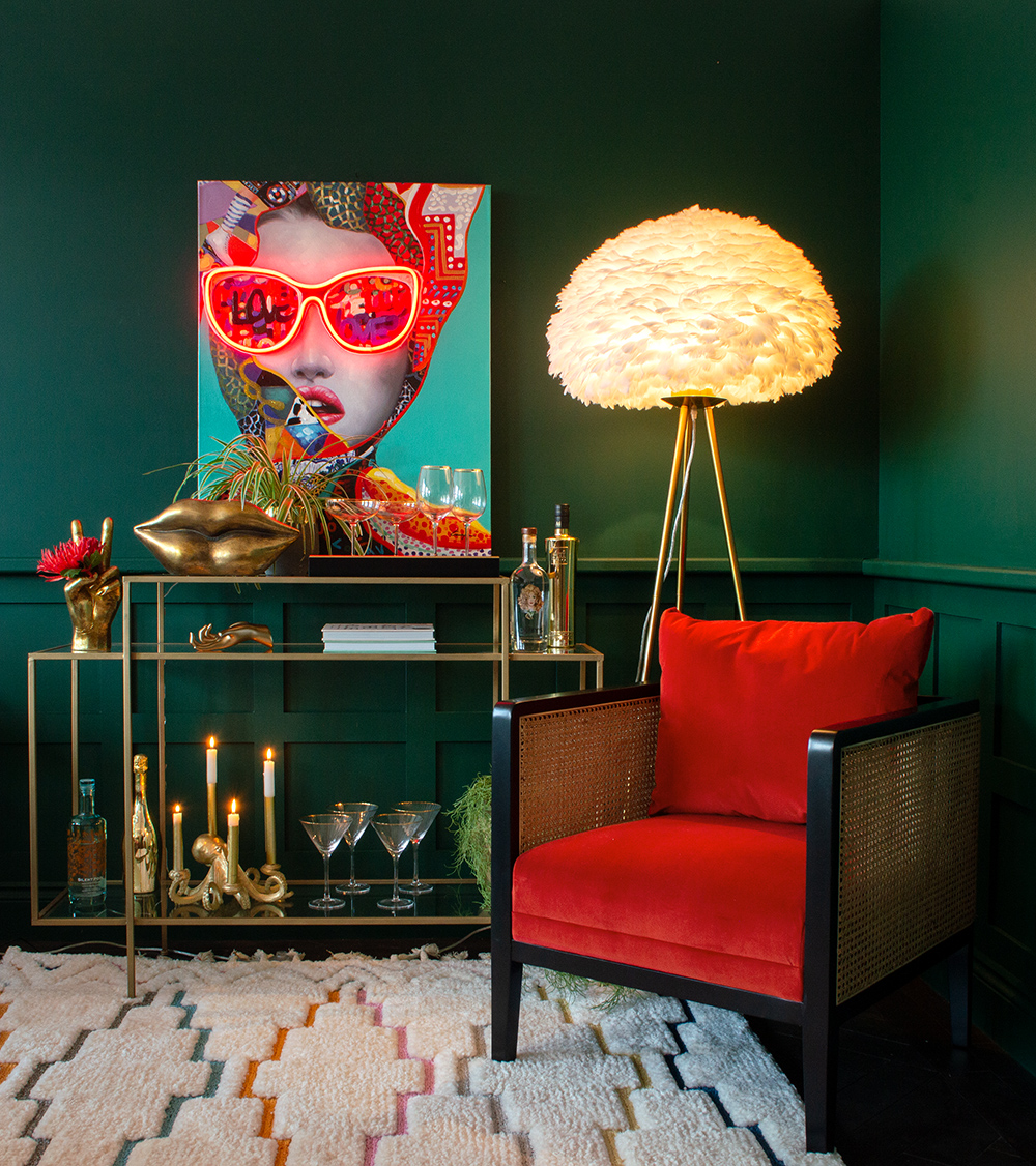 Green living room decor with neon artwork and red velvet armchair