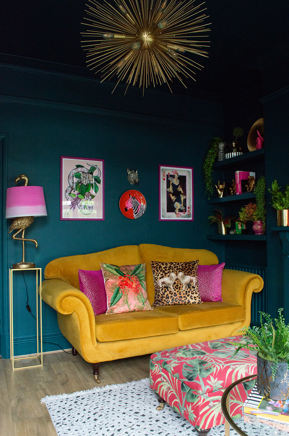 Moody living room decor with colourful artwork, mustard yellow velvet sofa and sunburst pendant light