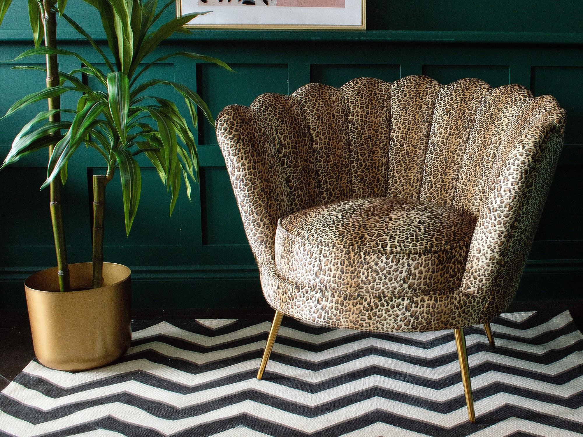 A leopard print armchair on a black and white pattern rug next to a potted bamboo plant
