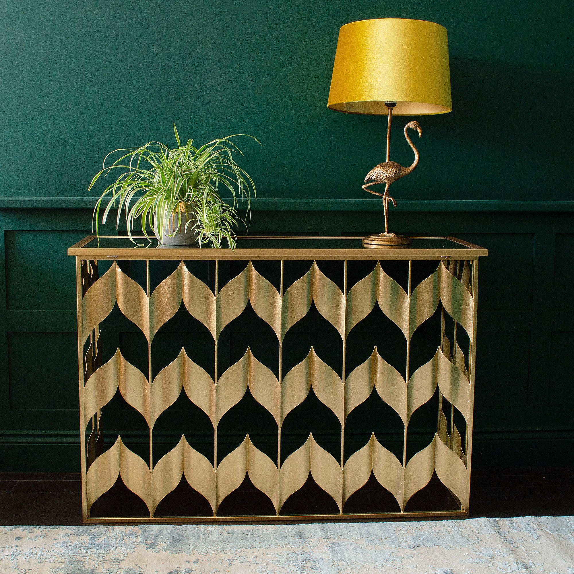 A gold console table with a lamp and a plant pot