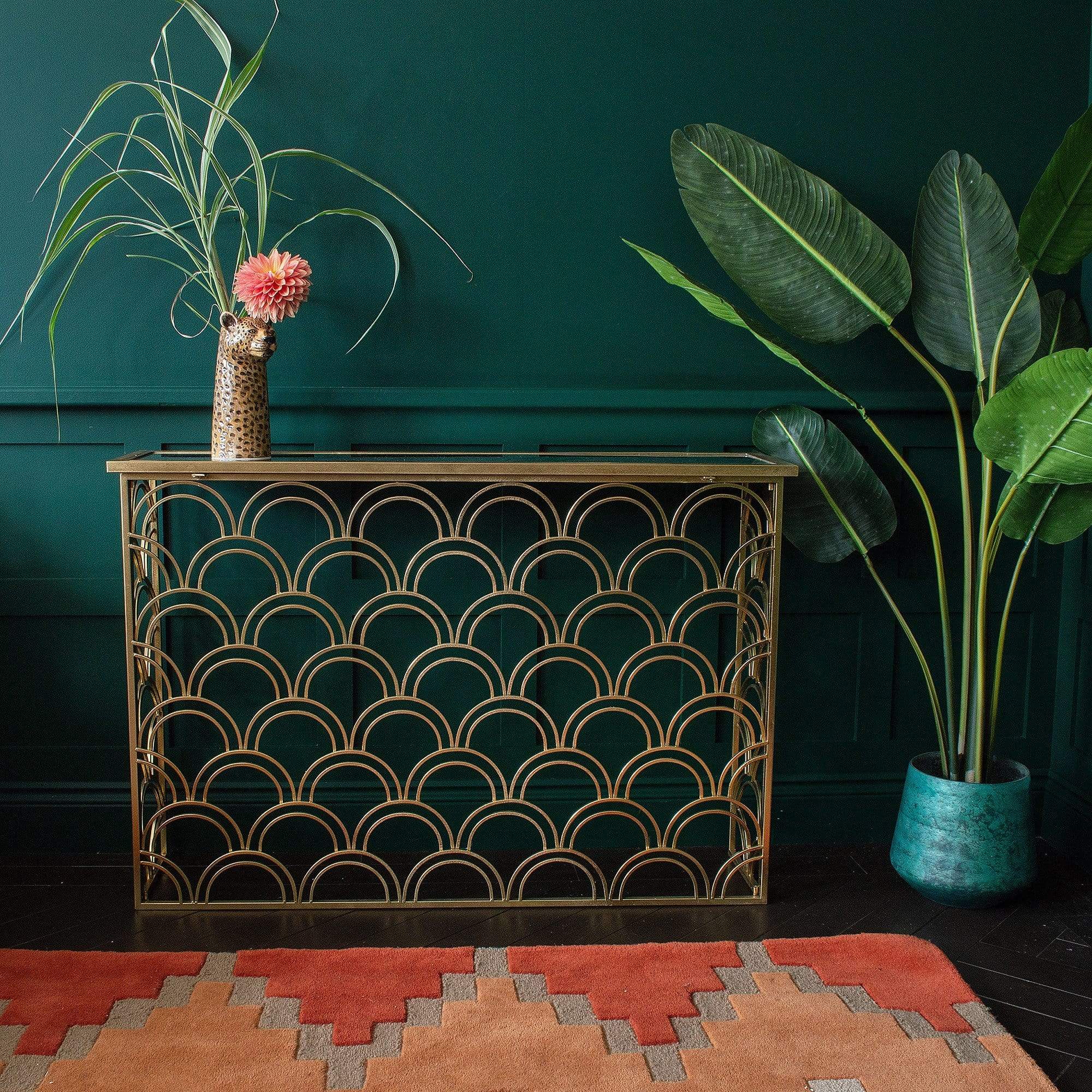 A gold console table with a flower vase next to a plant pot